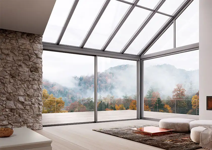 Solarlux serre met glazen schuifwanden en panoramisch uitzicht op een groen bos